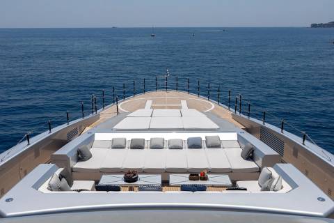 Luxurious deck seating and sunpads offer the perfect spot to relax on this elegant yacht cruising the azure sea.