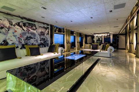 Luxurious yacht interior features a striking floral mural, plush white sofas, and a sleek, reflective coffee table overlooking the ocean.