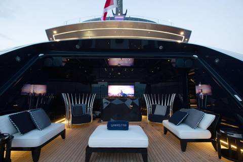 Luxurious outdoor lounge area on a yacht features comfortable seating, a large screen, and ambient lighting for evening relaxation.