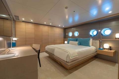 Luxurious porthole windows illuminate this serene bedroom with a modern desk and ample closet space.