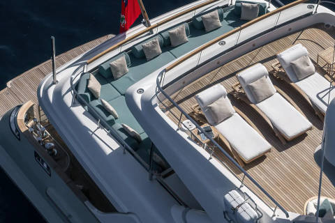 Luxurious white lounge chairs and teal cushions await on the sun-drenched deck of this elegant yacht.