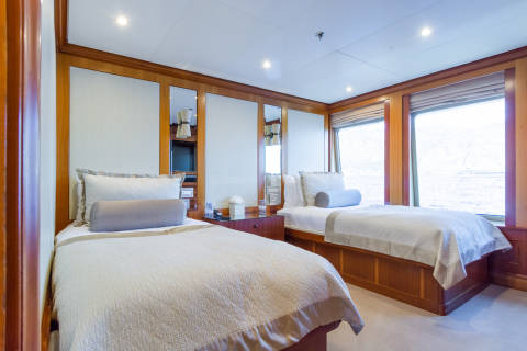 Luxurious twin beds with plush bedding and elegant wood paneling create a serene retreat with stunning ocean views.