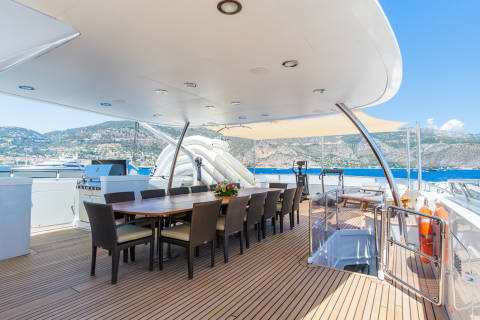 Enjoy al fresco dining on the spacious deck of a luxury yacht with a stunning mountain backdrop.