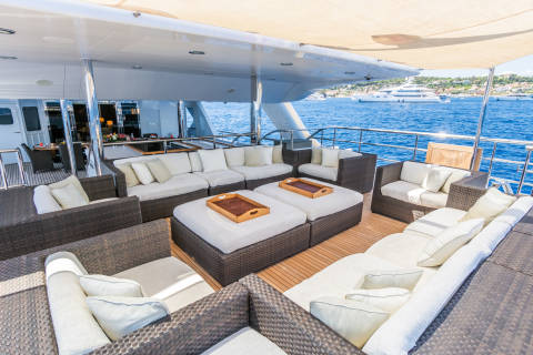 Luxurious outdoor seating on a yacht deck offers a prime spot to enjoy the sparkling blue waters and distant coastline.