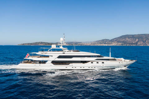The luxurious yacht "The Wellesley" cruises through the azure waters off a picturesque coastline.