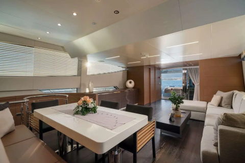 A modern and well-furnished living space with a dining table, comfortable seating, and large windows providing natural light and a view of the outdoors.