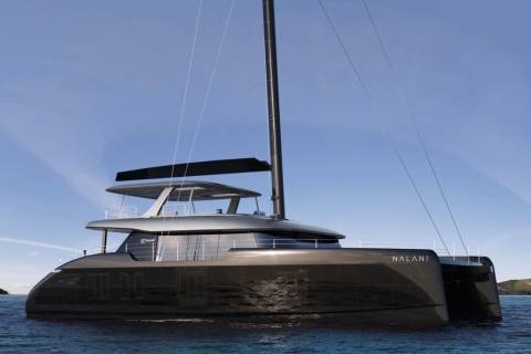 Sleek black catamaran Nalani glides through calm blue waters under a clear sky.