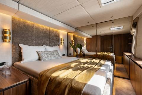 Luxurious yacht cabin features a plush bed, ambient lighting, and mirrored walls for an expansive feel.