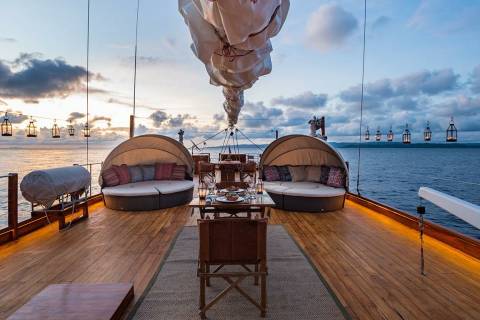 Dine al fresco on the deck of a luxury yacht as the sun sets over the tranquil ocean.