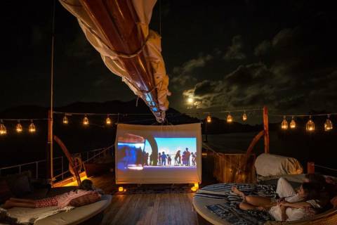 Enjoy a magical outdoor movie night under the moonlit sky on a luxurious yacht deck.