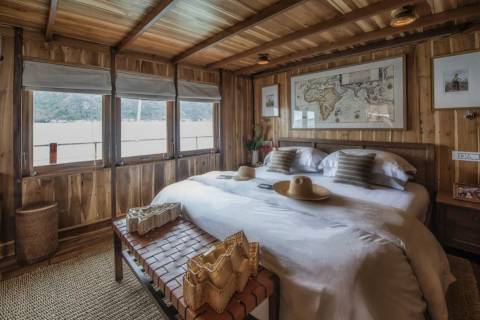 Luxurious wooden interiors and a large world map create a cozy and adventurous atmosphere in this unique bedroom.