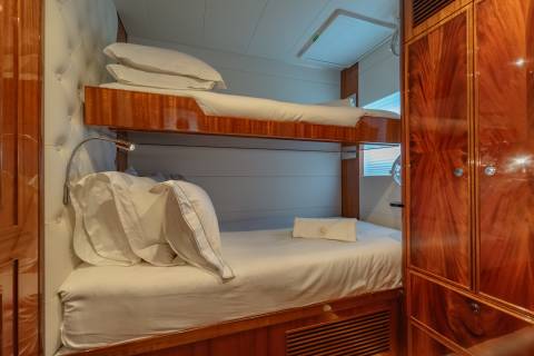 Luxurious bunk beds with plush white linens and a polished wood finish offer a comfortable retreat on board.