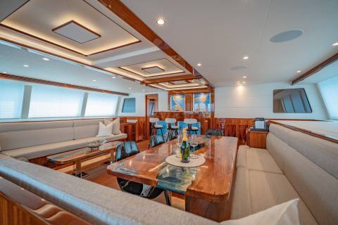 Luxurious yacht interiors feature a spacious dining area with a unique epoxy table and a well-appointed bar.