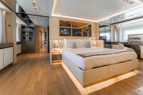 Luxurious yacht interiors feature a spacious bedroom with a king-sized bed, ambient lighting, and elegant artwork.