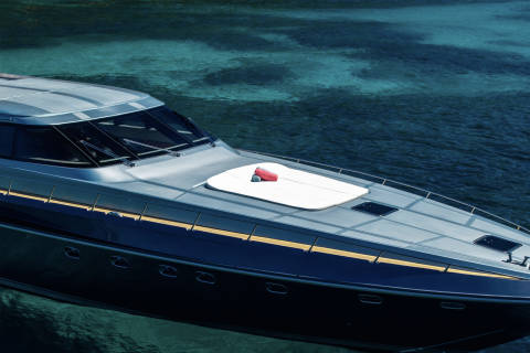 A sleek yacht glides through crystal-clear turquoise waters under a bright sun.