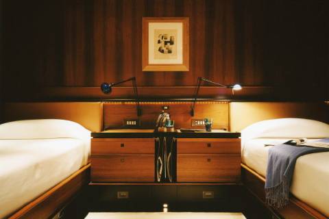 Luxurious twin beds are perfectly appointed with reading lamps and elegant wooden nightstands in this sophisticated cabin.