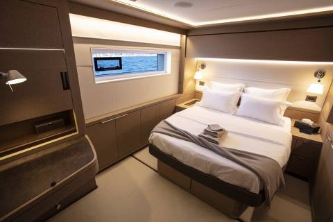 A cozy and modern bedroom with a large window overlooking the ocean, featuring a comfortable bed, built-in storage, and subtle lighting.