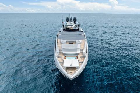 A sleek white yacht glides across the tranquil blue ocean, featuring a luxurious hot tub on its bow.