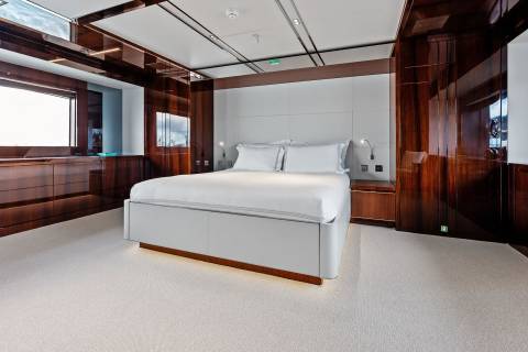 Luxurious yacht bedroom features a plush king-size bed, rich wood paneling, and ambient lighting for ultimate comfort.