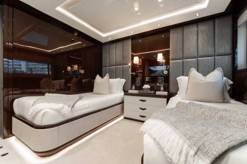 A luxurious and modern bedroom with plush white bedding, dark wood paneling, and recessed lighting creating a cozy and sophisticated atmosphere.