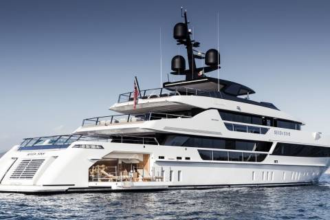 The luxurious superyacht Seven Sins glides through calm blue waters under a clear sky.