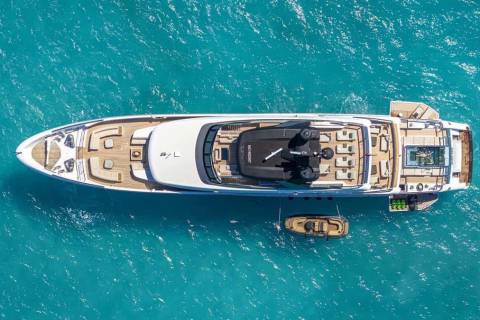 A luxurious yacht floats serenely in crystal-clear turquoise waters, complete with a tender and a refreshing pool on its deck.