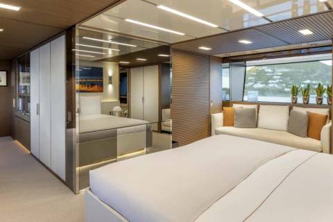 Luxurious yacht interiors feature a spacious bedroom with a plush sofa and a stunning view of the ocean.