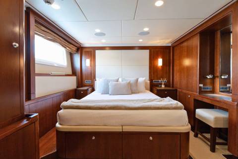 Luxurious wood paneling and plush bedding create a serene master suite aboard this elegant yacht.