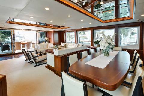 Luxurious yacht interiors feature a spacious lounge with plush seating and a formal dining area overlooking the water.