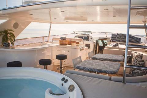 Relax in the sun-drenched jacuzzi aboard this luxurious yacht, surrounded by plush seating and elegant dining areas.
