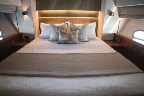 Luxurious yacht accommodations feature a plush bed with decorative pillows and a calming neutral palette.
