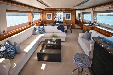 Luxurious yacht interiors offer breathtaking ocean views through expansive windows, complemented by elegant furnishings and a sophisticated bar area.