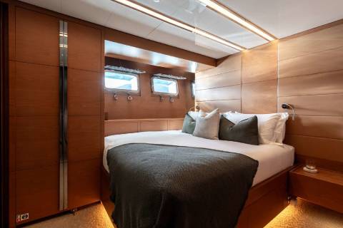 A cozy and well-appointed bedroom interior with wooden paneling, recessed lighting, and a comfortable-looking bed with plush bedding.