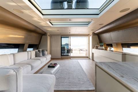 A spacious and modern interior of a recreational vehicle, featuring a comfortable seating area, a kitchen, and large windows that allow natural light to flood the space.