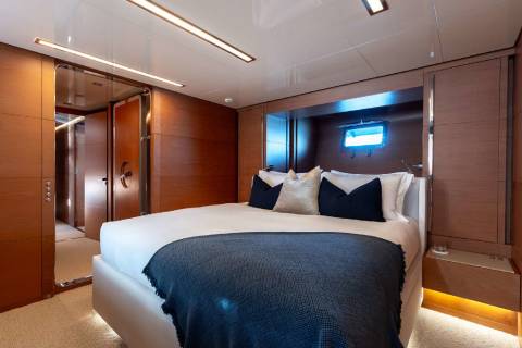 A cozy and modern bedroom with a large bed, wooden paneling, and recessed lighting, creating a warm and inviting atmosphere.