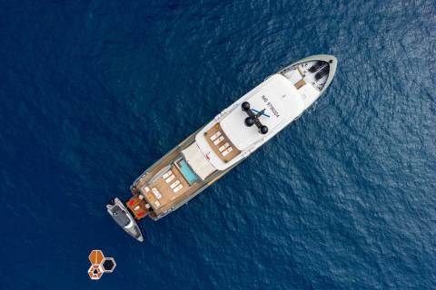 A luxurious yacht floats serenely on the deep blue ocean, accompanied by a smaller tender and a unique floating platform.