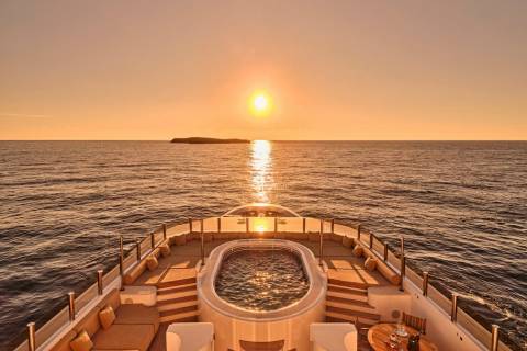 A luxurious yacht's jacuzzi and sun deck offer a perfect vantage point for a breathtaking sunset over the ocean.