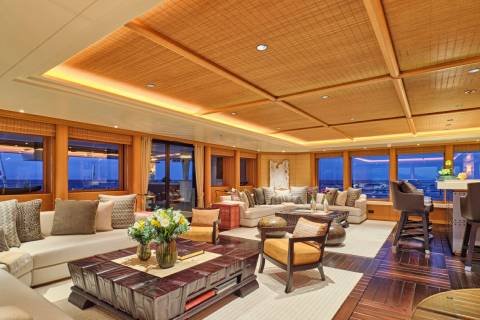 Luxurious yacht interiors feature a spacious lounge with comfortable seating, a large coffee table, and expansive windows offering ocean views.