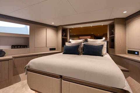 Luxurious yacht cabin features a comfortable bed with plush pillows and elegant wood finishes.