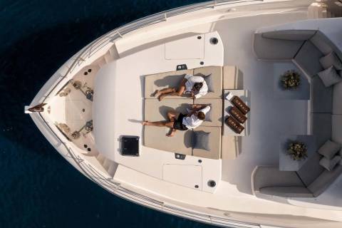 Two people relax on a luxurious yacht deck, enjoying the sun and the serene ocean waters.
