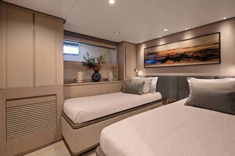This elegant stateroom features two twin beds, a soothing color palette, and a captivating abstract artwork above the headboard.