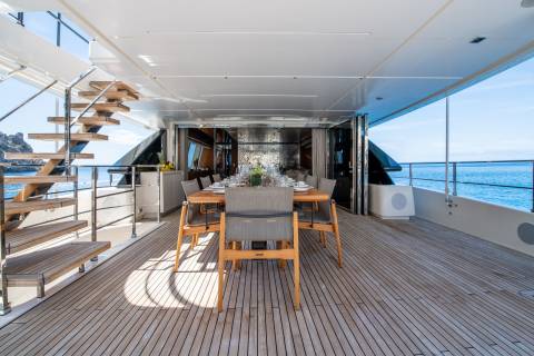 An elegant outdoor dining area on a yacht offers a picturesque setting for a meal with a view of the sparkling blue sea.