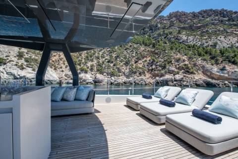 Relax on the sun-drenched deck of a luxury yacht, surrounded by the rugged beauty of a Mediterranean coastline.