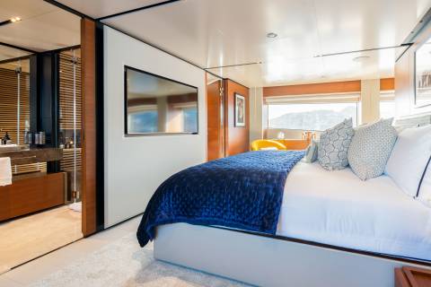 Luxurious yacht accommodations offer a serene retreat with a plush blue duvet and stunning ocean views.