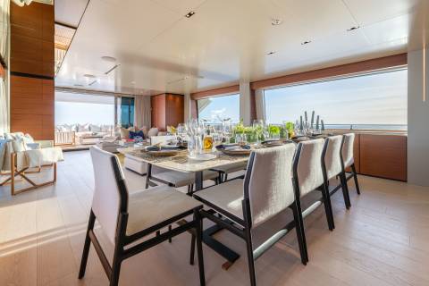 A beautifully set dining table on a yacht awaits guests with a stunning ocean view.