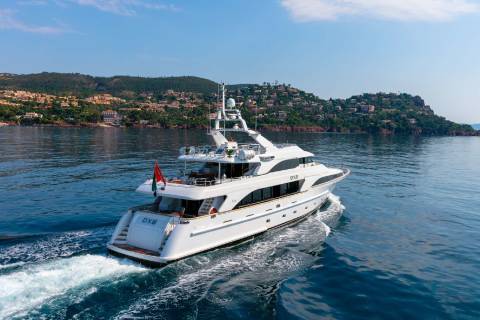 A luxurious white yacht cruises through the sparkling blue waters of the Mediterranean Sea under a clear sky.