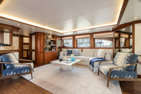 Luxurious yacht interiors feature plush seating, elegant wood finishes, and panoramic windows overlooking a modern cityscape.