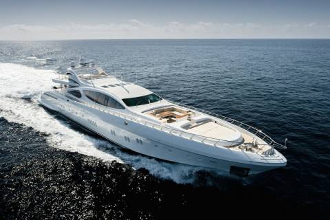 A sleek white yacht cuts through the deep blue ocean, leaving a trail of white foam in its wake.