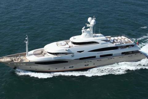A sleek, modern superyacht glides through the deep blue ocean, leaving a white wake in its powerful path.