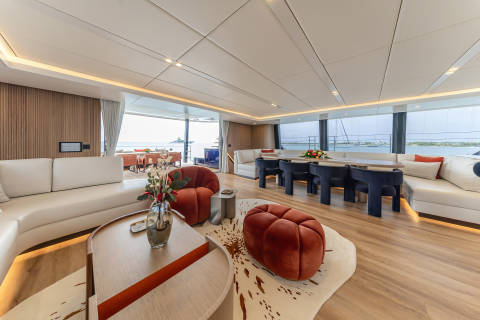A modern and luxurious living space with comfortable seating, a dining area, and large windows offering a scenic view of the surrounding landscape.
